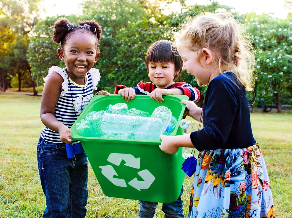 school kids holding recycling bin